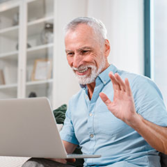 Smiling mature man having video call on laptop
