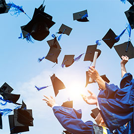 Graduating students hands throwing graduation caps in the air.