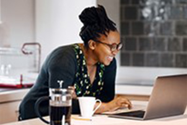 Woman at counter on laptop, drinking coffee