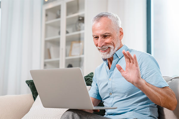 Smiling mature man having video call on laptop