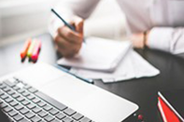 Student taking notes from a laptop screen